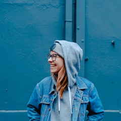Mara smiling in a denim jacket against a blue wall