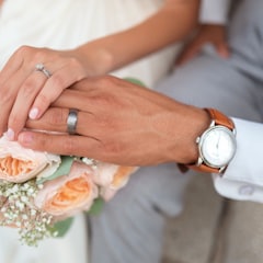 Two hands wearing wedding rings over a bouquet